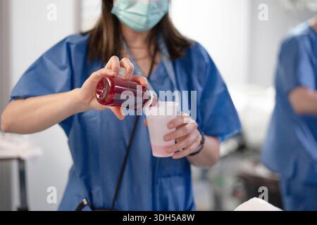 Pflegekräfte auf einer Intensivstation werden mit der fachkundigen Verwaltung der Patientenversorgung beobachtet, die blaue Peelings und Masken tragen und ihren Einsatz und ihre Professionalität in einem modernen Modell unterstreichen Stockfoto