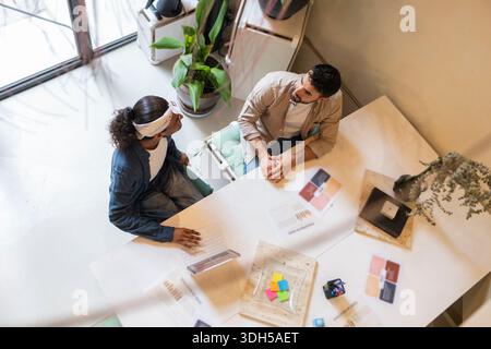 Ein vielseitiges Team von Kollegen, die in einem hellen, modernen Bürobereich mit Laptops und Dokumenten auf dem Tisch zusammenarbeiten, fördert Kreativität und Teamarbeit Stockfoto