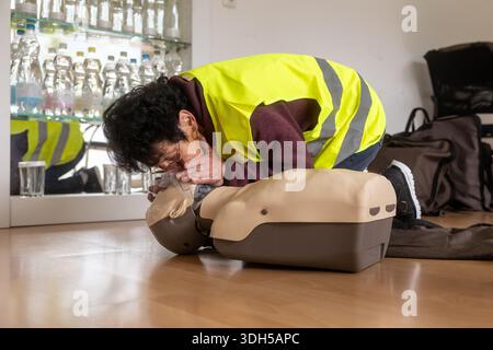 Eine Person in einer Sicherheitsweste übt die HLW an einer Trainingskuppe aus. Das Bild zeigt das Wesen der erste-Hilfe-Schulung und hebt die wesentlichen LIFE hervor Stockfoto
