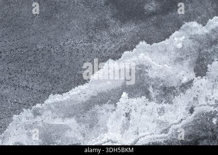 Eine abstrakte Nahaufnahme von Salzkristallen, die komplizierte Muster auf einer dunkelgrauen Oberfläche bilden. Die kontrastierenden Texturen erzeugen einen markanten visuellen Effekt, res Stockfoto