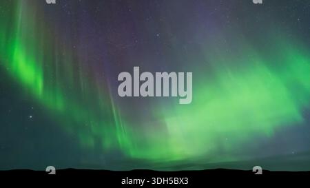 Ein atemberaubendes Panorama der aurora Borealis, das den Nachthimmel mit leuchtenden Grüntönen beleuchtet und das Naturwunder dieses atemberaubenden Atmo zeigt Stockfoto