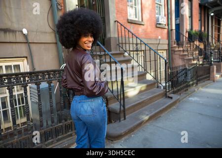 Eine junge Frau lächelt selbstbewusst in der New york City Street Stockfoto
