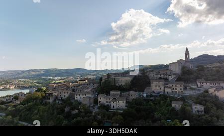 Die Drohnenfotografie macht einen atemberaubenden Blick auf eine historische italienische Stadt aus der Vogelperspektive. Steinhäuser und eine hoch aufragende Kirche sind von üppigem Grün und umgeben Stockfoto