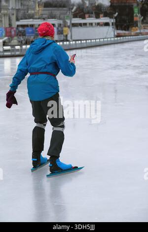 Speedskater in blauer Ausrüstung auf Eis mit schützender Kniestütze. Nordic Skating, Wintersport. Konzept des professionellen Skatings, des Wintersports Stockfoto