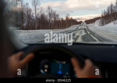 Persönliche Perspektive eines Touristen, der auf einer leeren verschneiten Straße fährt, Senja, Troms County, Norwegen Stockfoto