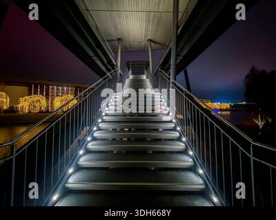 Beleuchtete Treppe zur Brücke, die die Volkswagen Autostadt mit dem Stadtbahnhof und dem Phaeno-Gebäude verbindet. Wolfsburg, Deutschland. Stockfoto