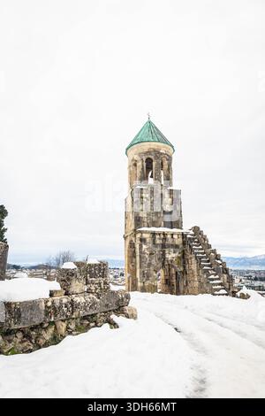 Historischer Glockenturm der Kathedrale von Bagrati in Kutaisi, Georgien, im Winter von Schnee umgeben. Malerischer Blick auf alte Architektur und Stadtpanorama unter Stockfoto