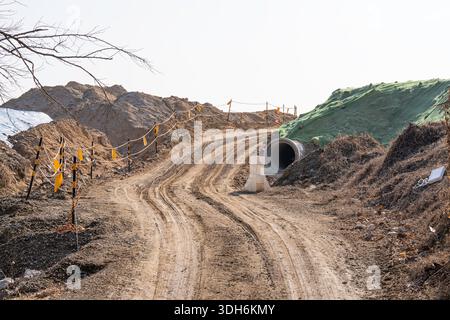 Baustelle mit unbefestigtem Weg und kargem Land unter klarem Himmel, die eine frühzeitige Infrastrukturentwicklung und weite Freiflächen für zukünftige Projekte zeigt Stockfoto