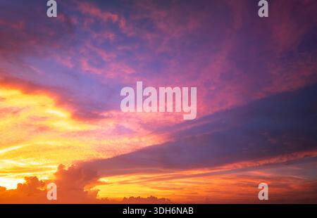 Heller Sonnenuntergang mit untergehender Sonne hinter leuchtenden orange und gelben Wolken Stockfoto