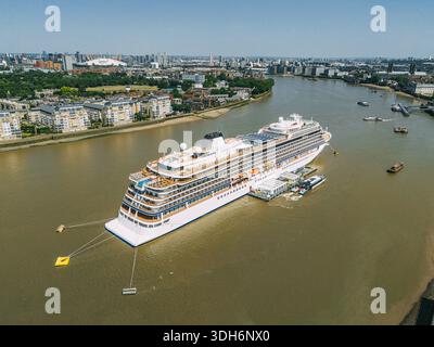 Aus der Vogelperspektive eines kolossalen Kreuzfahrtschiffs, das auf der Themse liegt und das sonnendurchflutete Stadtbild reflektiert, mit der O2 Arena, die sich von der Skyline Londo abhebt Stockfoto
