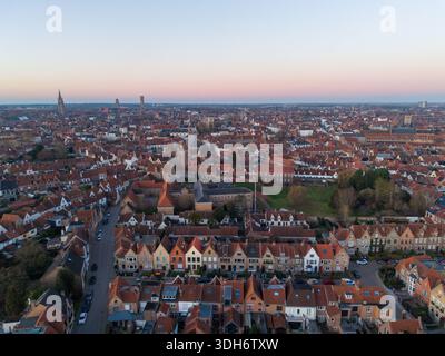 Blick aus der Vogelperspektive auf die Terrakotta-Dächer treffen auf das sanfte Licht der Dämmerung über den mittelalterlichen Türmen und bezaubernden Kanälen, Brügge, Flandern, Belgien. Stockfoto
