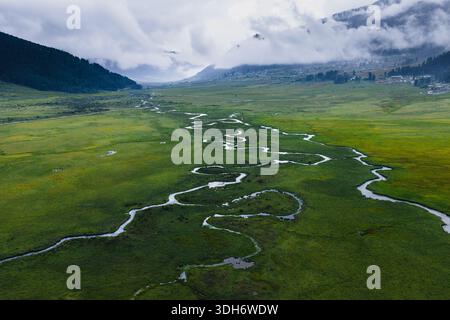 Aus der Vogelperspektive auf den Serpentinfluss, der sich durch den üppig grünen Talboden unter nebeligen Bergen schlängelt, Phobjikha Valley, Wangdue Phodrang, Bhutan. Stockfoto
