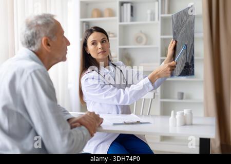 Weibliche Ärztin, die einen medizinischen Scan hält und Details zeigt, während sie männlichen Patienten konsultiert Stockfoto
