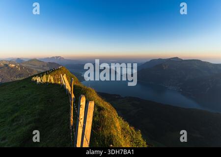 Ein atemberaubender Panoramablick von Niederbauen Kulm aus, auf das weitläufige Wasser des Vierwaldstättersees eingebettet in die majestätischen Schweizer Alpen. Der frühe More Stockfoto