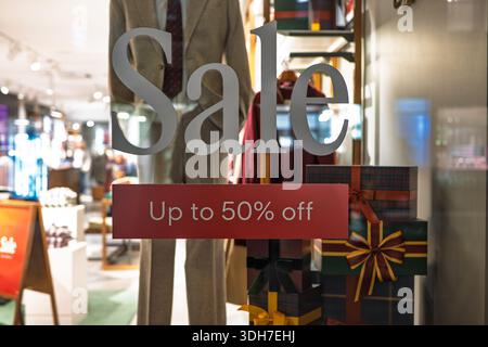 Schaufenstershop-Displays, die einen großen Ladenverkauf von bis zu 50% Rabatt anbieten. Weitwinkelansicht aus nächster Nähe, gekleidete Schaufensterpuppe und verpackte Geschenkboxen, geringe Tiefe Stockfoto