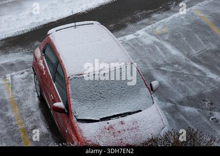 Von oben nach unten, erhöhter Blick auf die Neuschneedecke in einem geparkten Auto auf der Straße. Nahaufnahme, gewöhnliches Auto, keine Leute Stockfoto