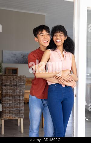 Diverse Paare stehen vor der Tür und umarmen Frau mit rosa Oberteil mit einem Uhrenmann mit Rost-T-Stück Stockfoto
