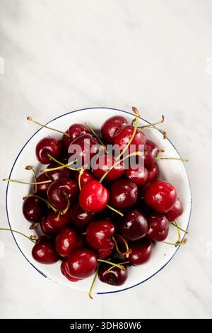 Draufsicht Platte mit Kirschen auf Marmoroberfläche Stockfoto