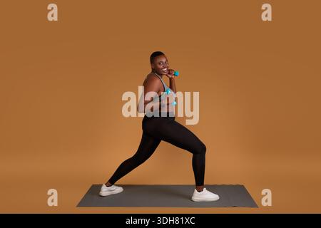 Mollig schwarz Training mit Hanteln auf Yogamatte Stockfoto