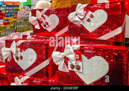 Liepaja, Lettland, 15. Januar 2026: Festliche Bonbons zum Valentinstag mit roten Pailletten, weißen Herzen und Bögen, die für romantische Geschenke ausgestellt werden. Stockfoto