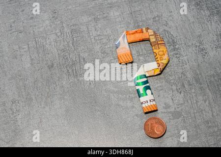 Fragezeichen aus einer Euro-Banknote mit einer Cent-Münze anstelle eines Punktes auf strukturiertem Hintergrund Stockfoto