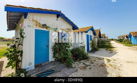 Port de Talais, New Aquitaine, Gironde, Frankreich - 17. Juni 2022. Eine Reihe von kleinen Holzhütten, weiß gestrichen mit hellblauen Türen und Zierleisten, und Stockfoto