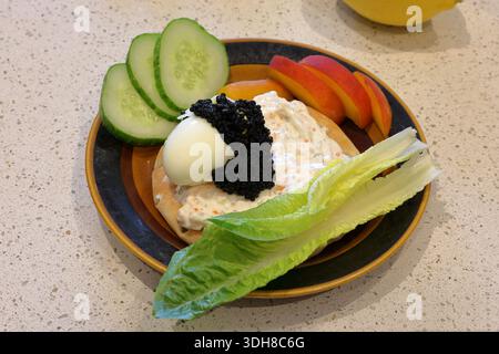 Hausgemachtes, frisches und gesundes Sandwich. Mit gekochtem Ei, schwarzem Fisch-Rum, Salat, Gurkenscheiben, Obst und Zitrone. Eine davon eine braune und schwarze Platte. Stockfoto