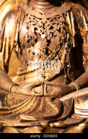 Nahaufnahme einer goldenen Buddha-Statue mit detaillierten Händen in Meditationsmudra, die Frieden, Spiritualität und Erleuchtung mit komplizierten Ornamenten symbolisieren Stockfoto