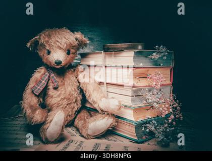 Vintage Teddybär, der neben alten Büchern sitzt, mit getrockneten Blumen auf gelben Seiten. Stillleben im Retro-Stil Stockfoto