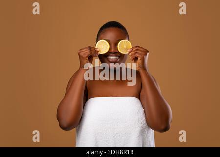 Schwarze Frau, die die Augen mit orangefarbenen Hälften bedeckt Stockfoto