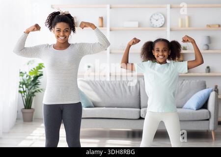 Starke afroamerikanische Mutter und Tochter zeigen ihre Muskeln Stockfoto