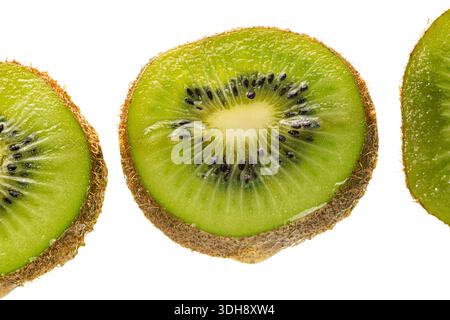 Drei Scheiben grüne Kiwis. Die mittlere Schicht wird halbiert. Die Schichten sind in einer Reihe angeordnet Stockfoto