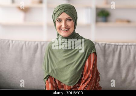Porträt Einer Lächelnden Älteren Muslimischen Dame, Die Zu Hause Hijab Trägt Stockfoto
