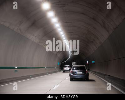 Autos, die in einem modernen Betontunnel mit künstlicher Beleuchtung fahren, städtische Infrastruktur, sicherer Straßenverkehr, Reisekonzept, Tunnelverkehr. Stockfoto