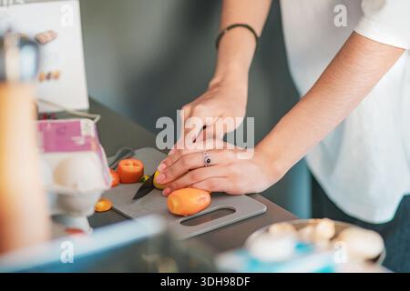 Nahaufnahme der Hände einer jungen Frau, die Paprika auf einem Schneidebrett in ihrer Küche schneidet, Lebensmittelkonzept. Stockfoto