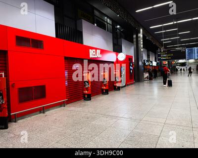 Krakau, Polen - 12. Januar 2026: Großer Blick auf eine rote Staffelfront in einem modernen Krakauer Flughafenterminal, Reisende mit Koffern kommen vorbei. Stockfoto