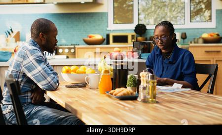 Junge Paare verfolgen ihre Ausgaben und erledigen ihre Haushaltsfinanzen, sitzen zusammen am Küchentisch mit Quittungen, Taschenrechner und Laptop. Rechnungsberechnung, verantwortliche Finanzplanung. Stockfoto