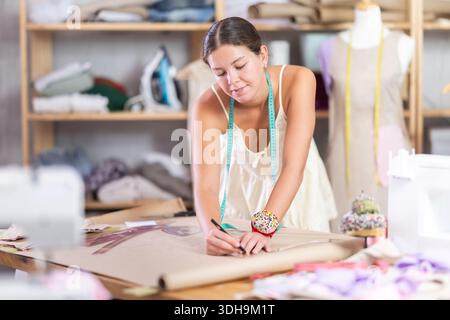 Die Schneiderin zeichnet Muster mit gebogenen Linealen Stockfoto