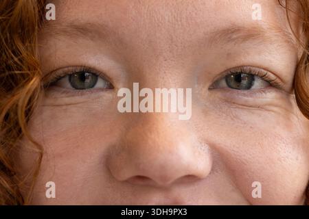 Teenagerin lächelt sanft, zeigt Sommersprossen und grünlich-graue Augen in der Nähe des Zimmers Stockfoto