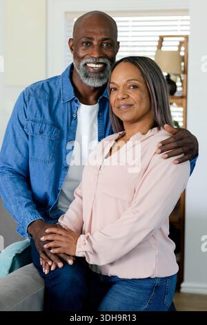 Verschiedene Paare tragen ein Jeansshirt und eine rosa Bluse, posieren auf dem Sofa, an Jalousien und einer Lampe Stockfoto