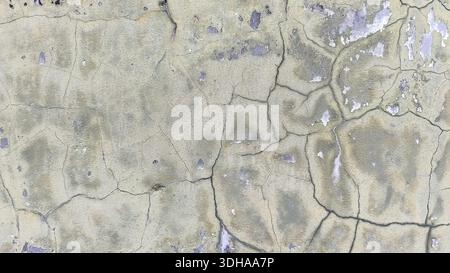 Nahaufnahme einer alten, verwitterten Betonwand mit tiefen Rissen, abblätternder Farbe und einer verstörten Textur in gedämpften Grau- und Beigetönen. Stockfoto