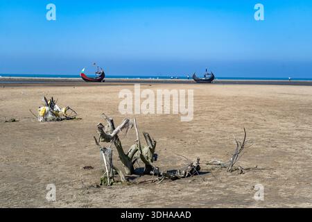 Traditionelles Mondboot (Sampan) an der Küste von Teknaf, Cox's Bazar. Buntes Holzfischboot an einem Sandstrand unter klarem blauen Himmel Stockfoto