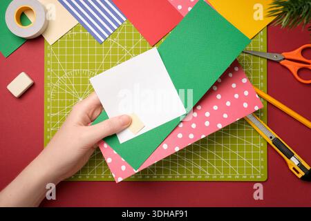 Ein Gnom-Handwerk herstellen. Die Hände halten drei Papierstücke. Kreativer Prozess. Stockfoto