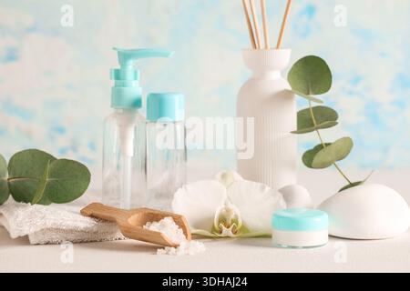 Komposition mit Spa-Accessoires, Kosmetikprodukten und Eukalyptuszweigen auf Leuchttisch in der Nähe der Farbwand Stockfoto