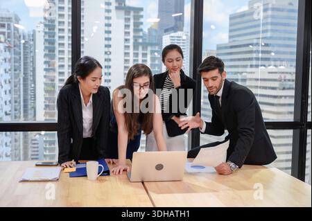 Multiethnisches Business-Team diskutieren und Brainstorming von Business-Plan mit Laptop auf Holzschreibtisch im Coworking Space Stockfoto