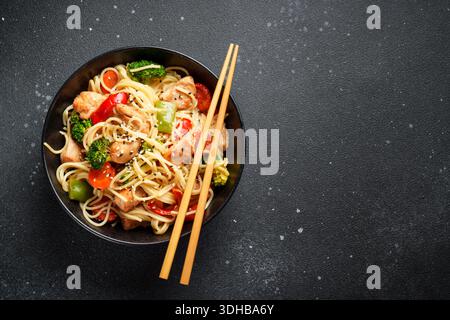 Hähnchen mit Gemüse und Nudeln auf schwarzem Hintergrund anbraten. Asiatische Küche. Draufsicht mit Platz für die Konstruktion. Stockfoto