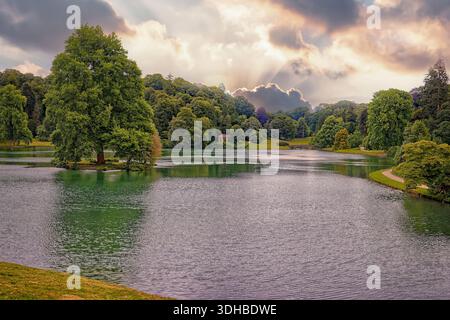 Sonnenuntergang über einem englischen Park mit einem Baum auf einer Insel im See. Stockfoto