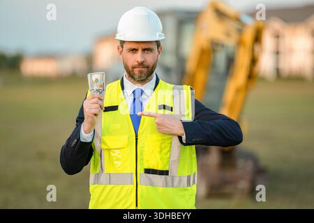 Erfolgreiches Geschäft. Finanzinvestitionen. Geldbudget. Erfolgreicher Bauinvestor, Mann, der mit dem Finger auf Geld zeigt. Geschäftsleute zählen Geld vor Ort Stockfoto