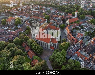 Blick aus der Vogelperspektive auf die große Liebfrauen-Ueberwasser-Kirche mit ihrem markanten Turm und roten Dachziegeln inmitten eines Meeres aus grünen Bäumen und traditionellem Bauwerk Stockfoto