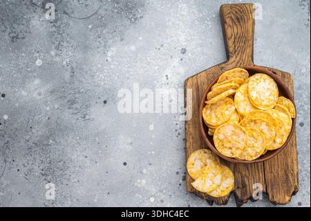 Knusprige Reischips in Holzschale gestapelt. Heller knuspriger Snack isoliert auf grauem Hintergrund Stockfoto